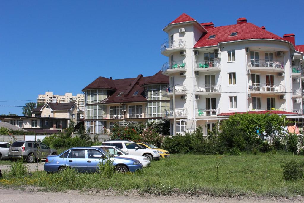 un gran edificio con coches estacionados frente a él en Skarlett Guest House, en Lazarevskoye