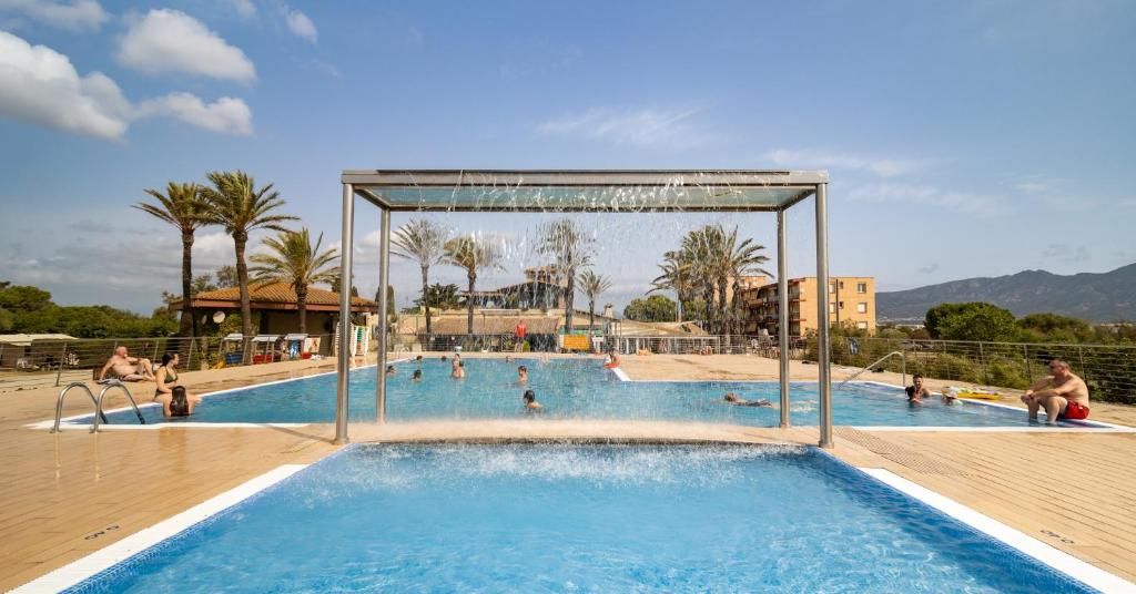 a pool at a resort with people in it at Camping Castell Mar in Empuriabrava