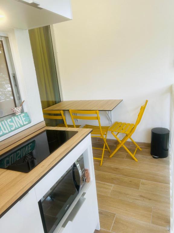 a kitchen with a table and a table and a chair at Studio Fresh&amp;Cosy Trois-Ilets - 3 étoiles-Hotel Carayou in Les Trois-Îlets
