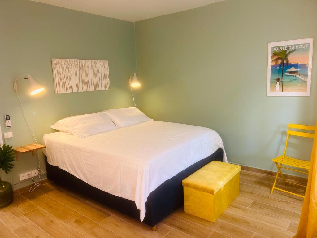 a bedroom with a white bed and a yellow stool at Studio Fresh&amp;Cosy Trois-Ilets - 3 étoiles-Hotel Carayou in Les Trois-Îlets