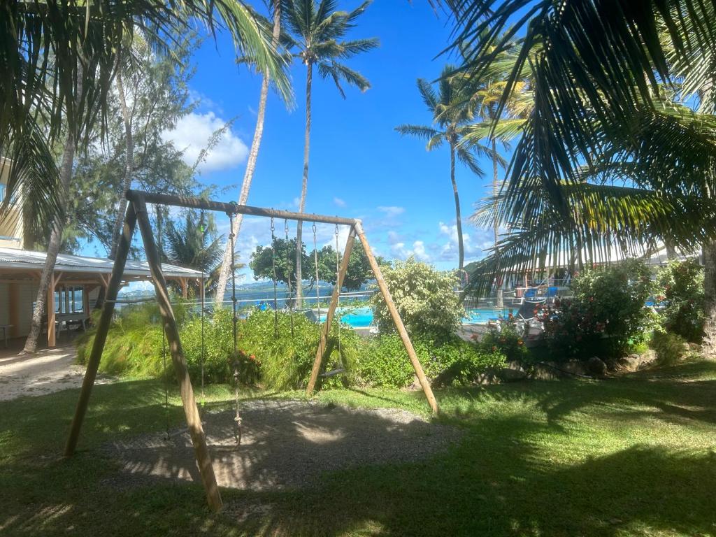 a swing set in a yard with a view of the ocean at Studio Fresh&amp;Cosy Trois-Ilets - 3 étoiles-Hotel Carayou in Les Trois-Îlets