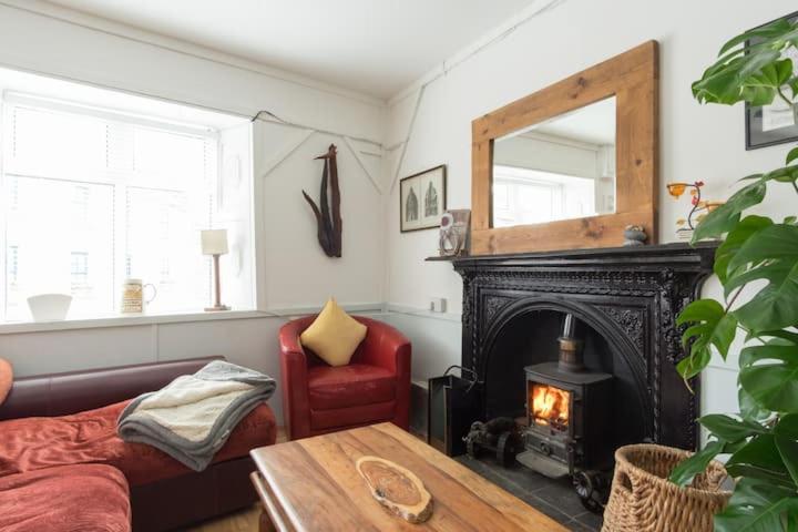 a living room with a fireplace and a red chair at Cosy & Comfy in Kinvara