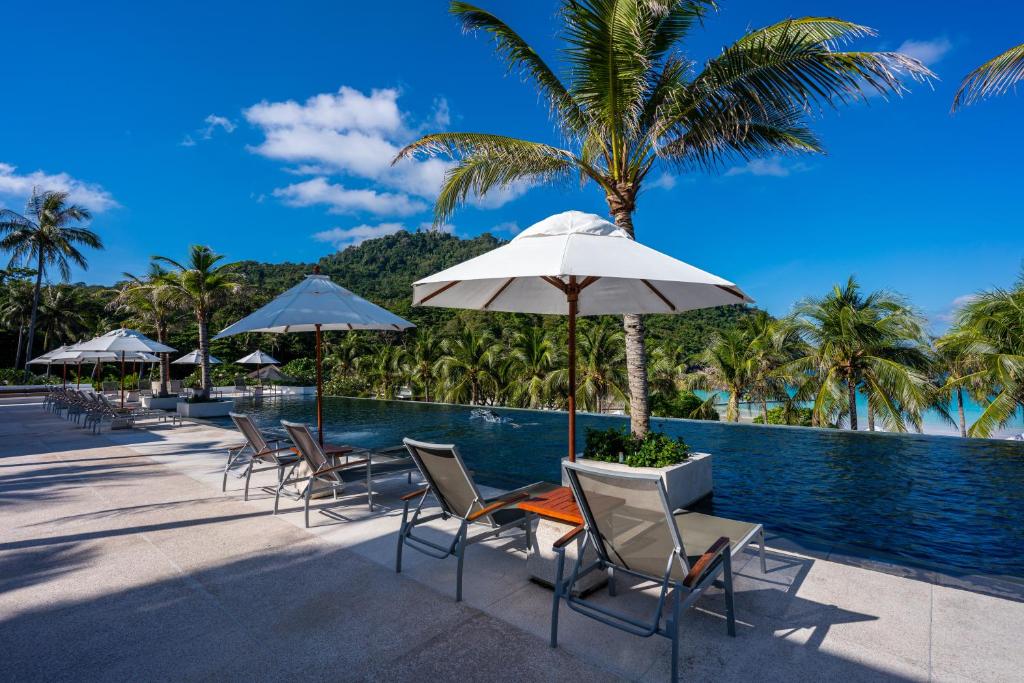 a group of chairs and umbrellas next to a swimming pool at The Racha in Ko Racha Yai 