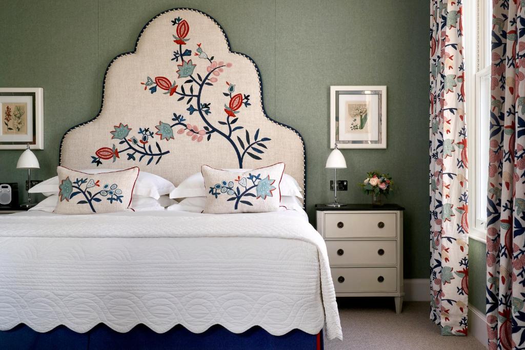 a bedroom with a white bed with a floral headboard at Haymarket Hotel, Firmdale Hotels in London