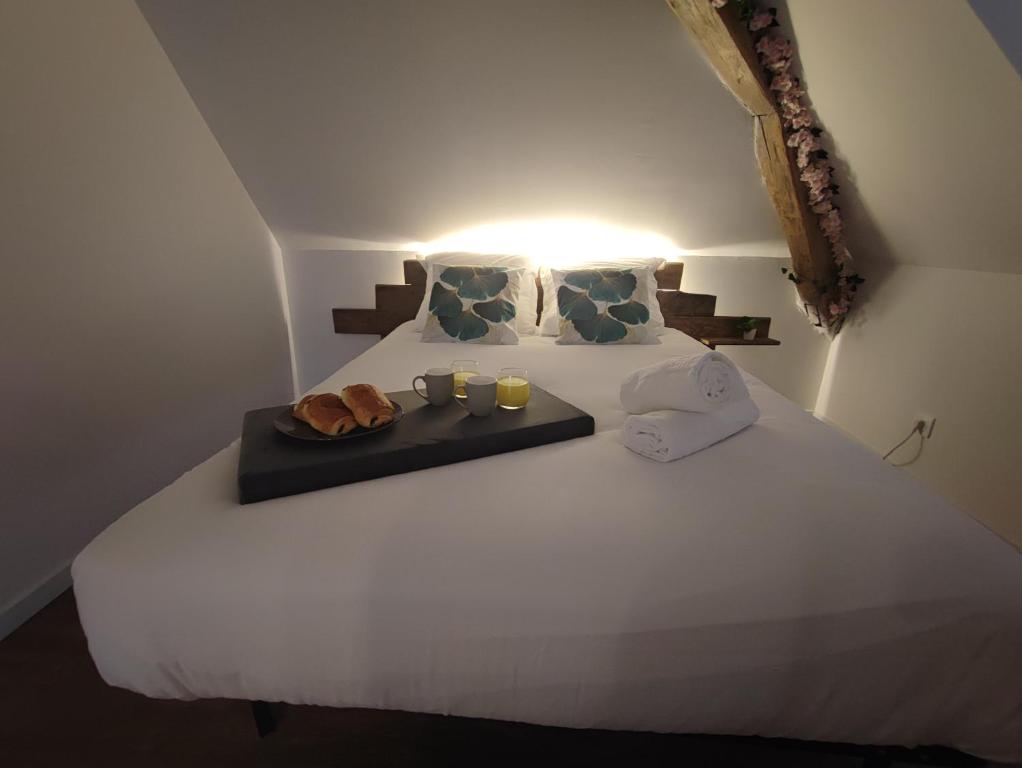 a white bed with two mugs and two candles on it at Edera in Saint-Aignan