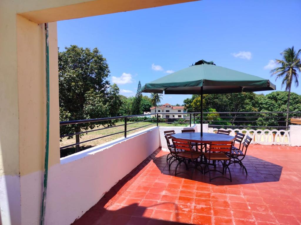 Happy Trails Home- Green Wood Estate Mtwapa في متوابا: طاولة وكراسي مع مظلة على الفناء