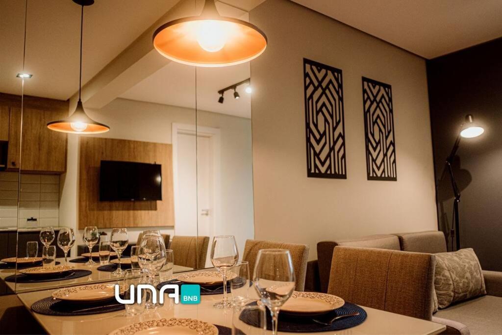 a dining room with a table with wine glasses at Studio contemporâneo no Parque Una com garagem in Pelotas