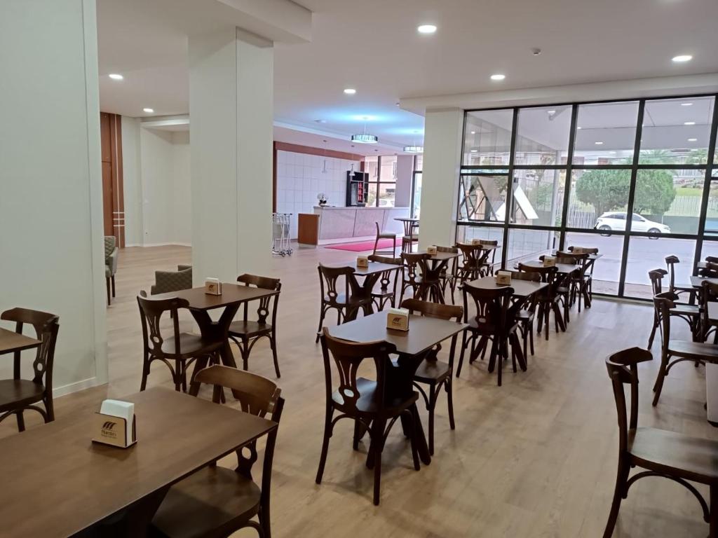HOTEL MAESTRO EXECUTIVE PATO BRANCO في باتو برانكو: مطعم فيه طاولات وكراسي في الغرفة