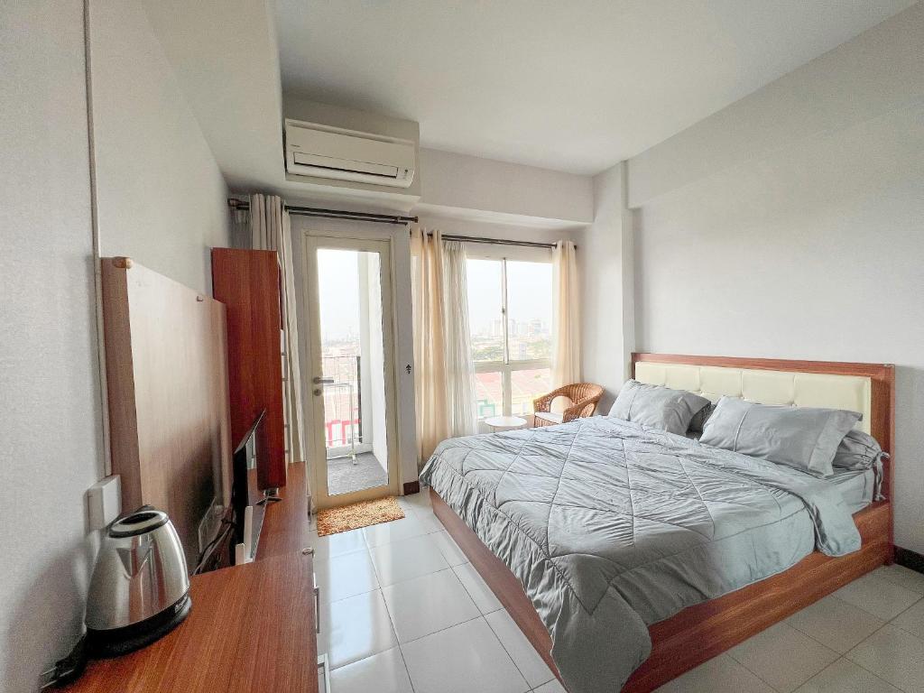 a bedroom with a bed and a large window at Campus Convenience at Scientia Apartment in Tangerang