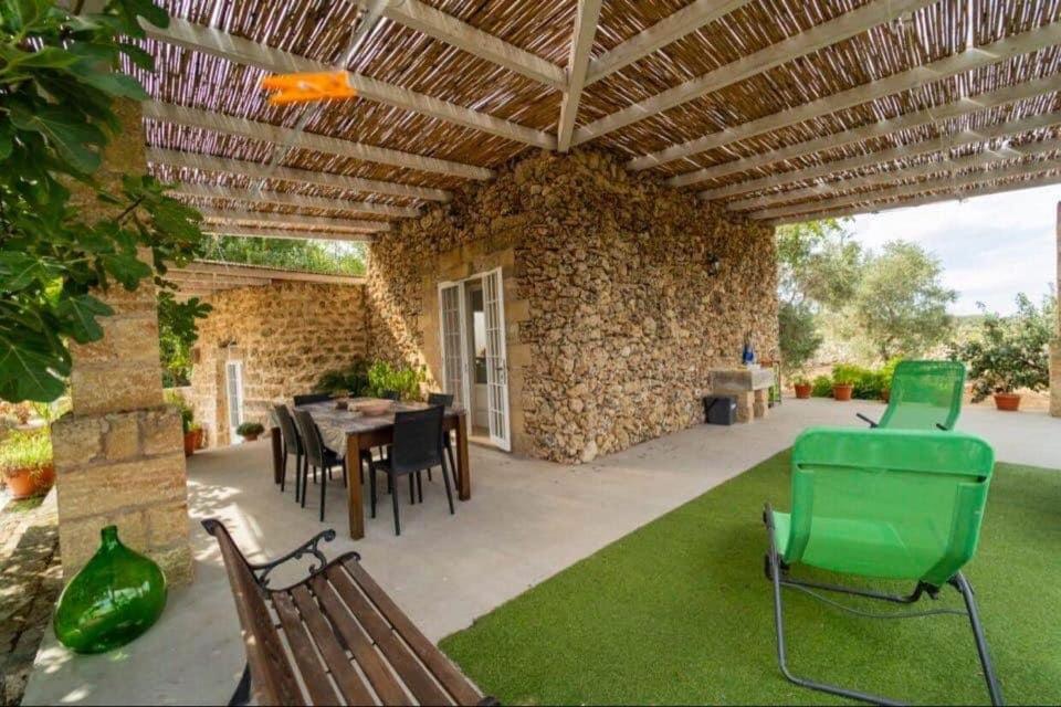 een patio met een tafel en stoelen en een stenen muur bij Tenuta Rosa Casa Salento Holidays in Taviano