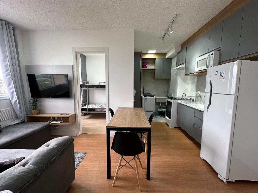 a kitchen with a table and a white refrigerator at TrevizZo Allianz Parque in Sao Paulo