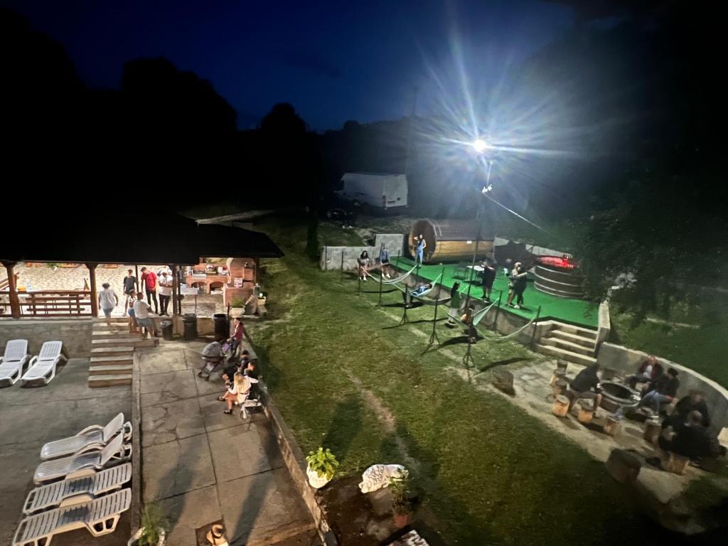 een groep mensen die 's nachts op het gras zitten bij Casa Radu lui Anghel in Bărbuleţu