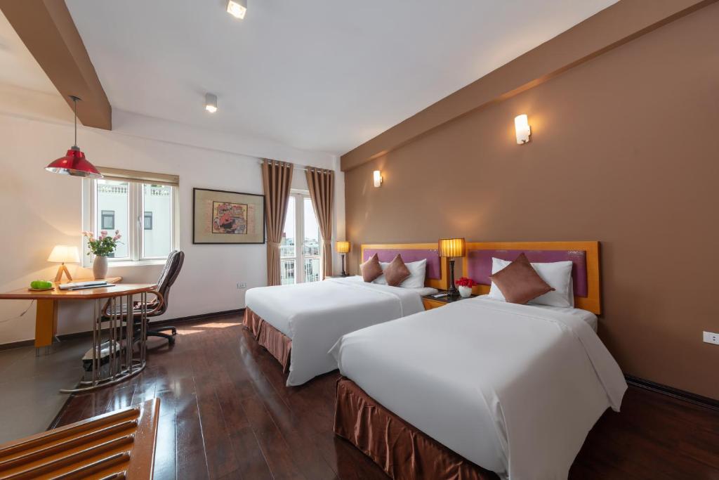 a hotel room with two beds and a desk at Golden Sunshine Villa Hotel and Travel in Hanoi
