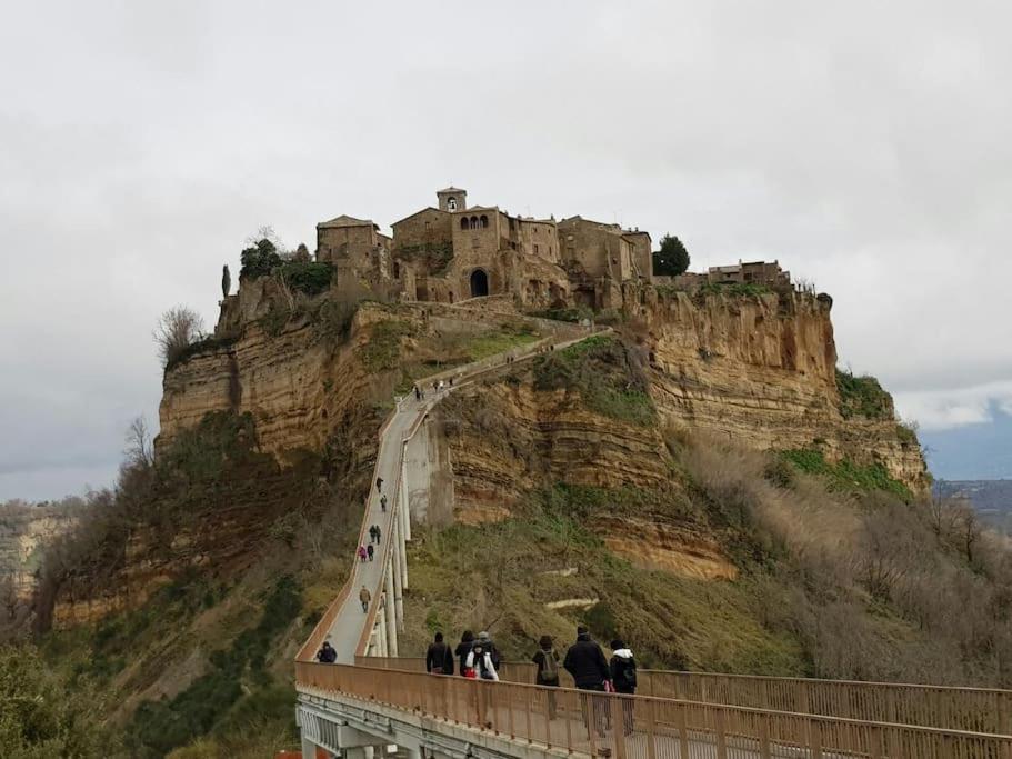 een groep mensen die op een brug staan met een kasteel op een berg bij il salotto dei calanchi in Bagnoregio