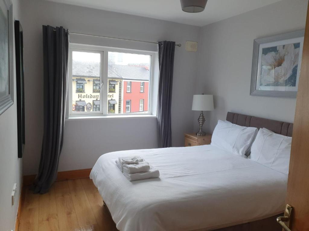 a bedroom with a large white bed with a window at Cosy beachfront apartment in Salthill Galway city in Galway