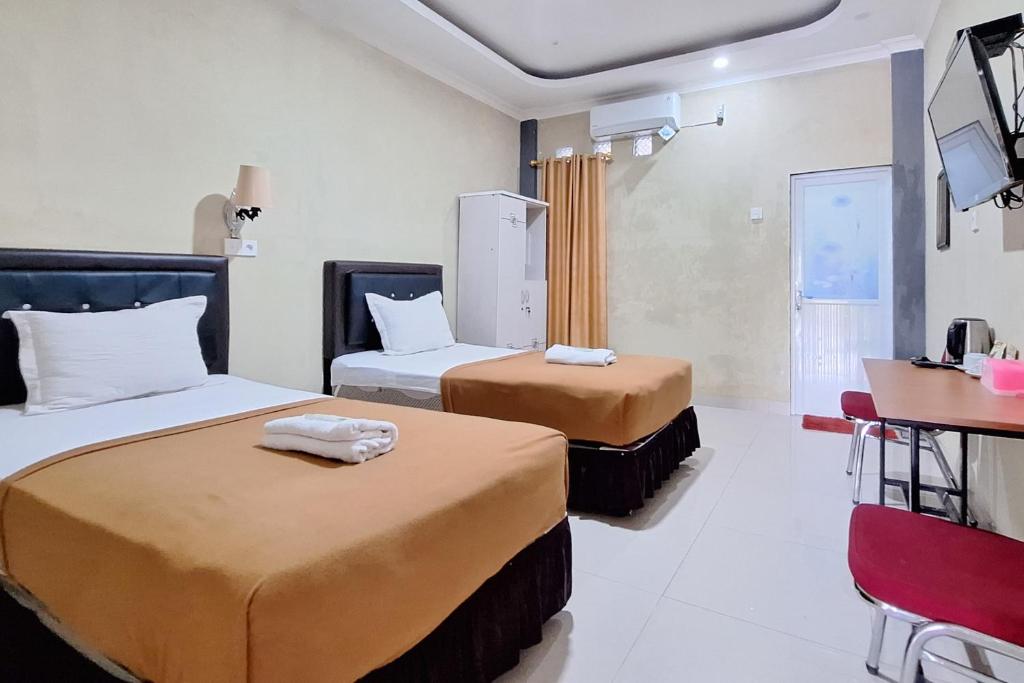 a hotel room with two beds and a desk at Hotel Jelita Mentawai Redpartner in Tua Pejat