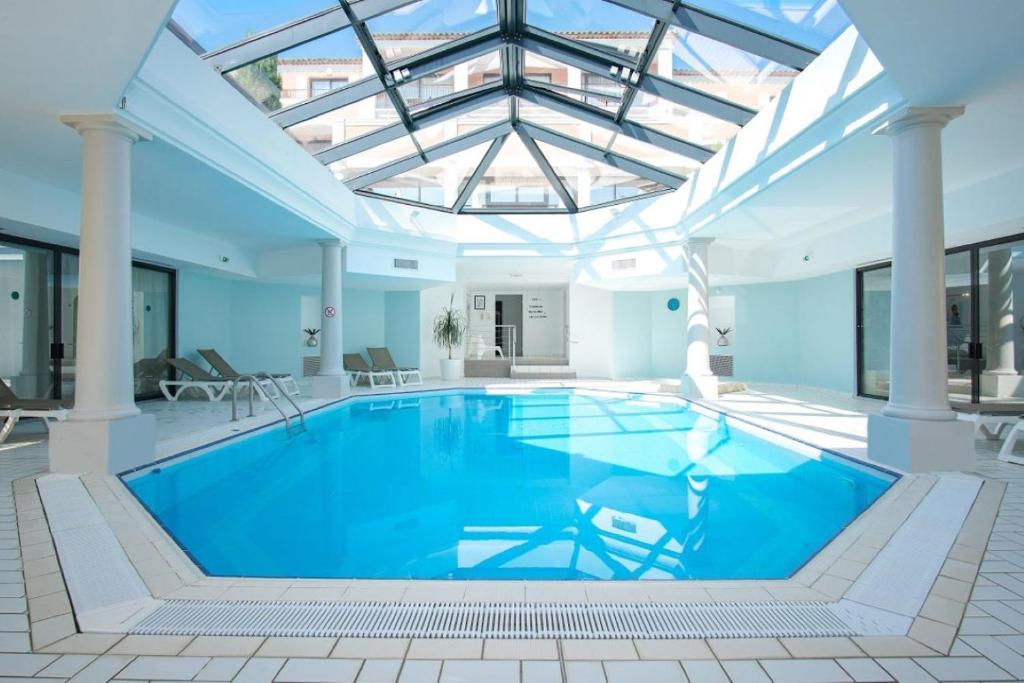 een groot zwembad met een glazen plafond bij Hôtel Les Jardins De Sainte-Maxime in Sainte-Maxime