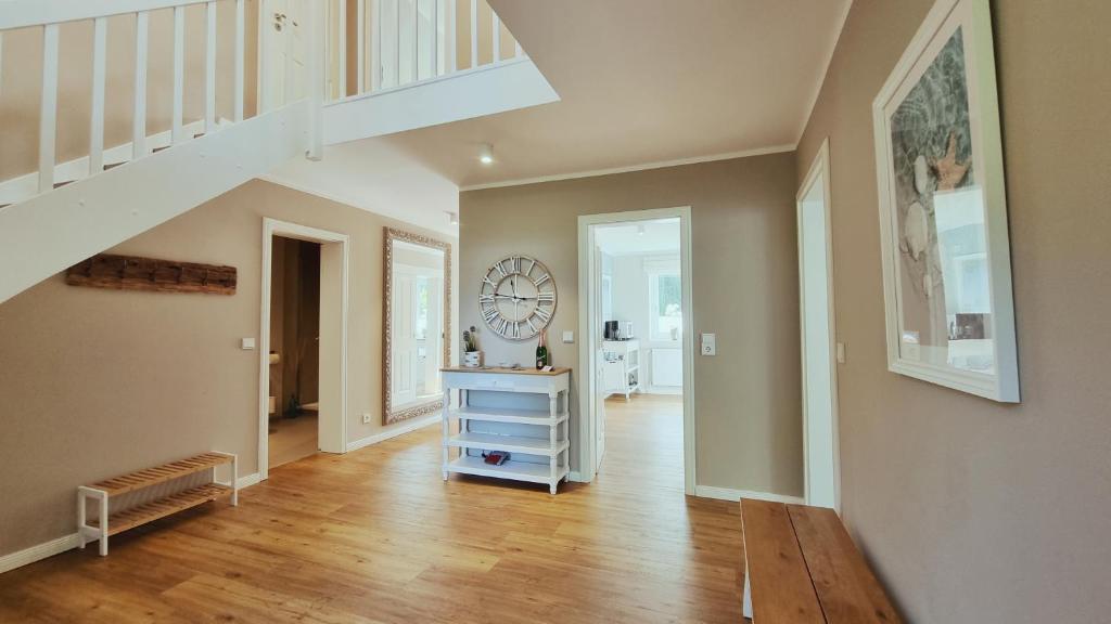 a room with a staircase and a dresser with a clock at Ferienhaus Küstenhuus Kalifornien an der Ostsee in Kalifornien