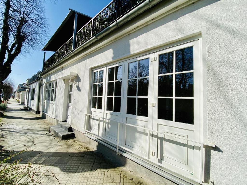 a building with white doors and windows on a sidewalk at Daisy in Warnemünde