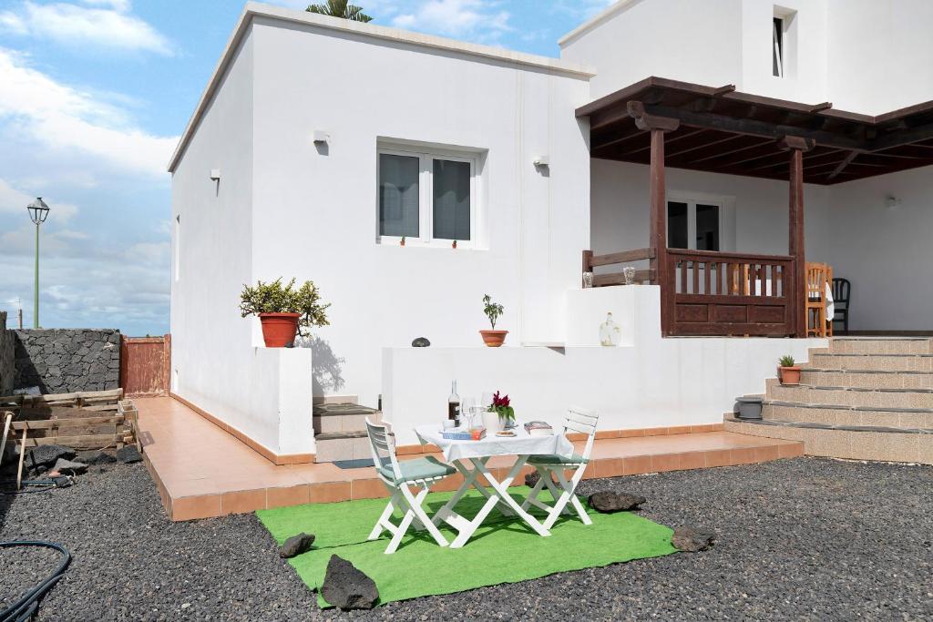 ein weißes Haus mit einem Tisch und Stühlen in der Unterkunft Casa Rosi in Tinajo