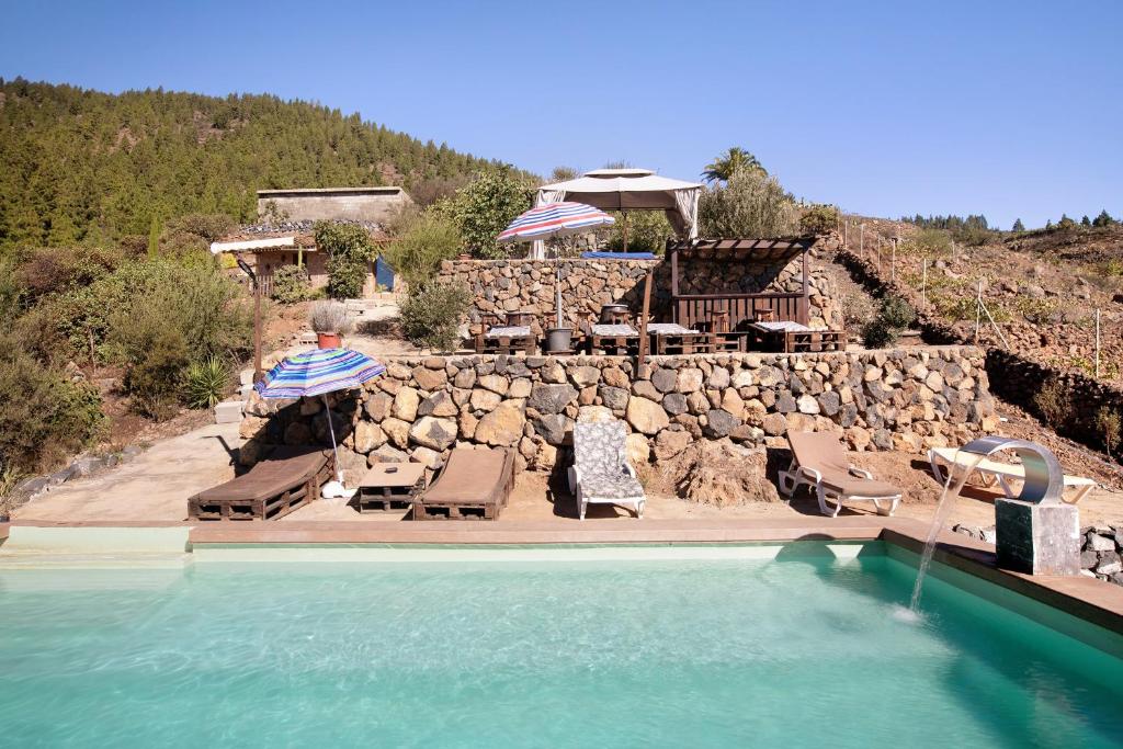 a swimming pool with lounge chairs and a stone wall at El Cazador 1 in Granadilla de Abona
