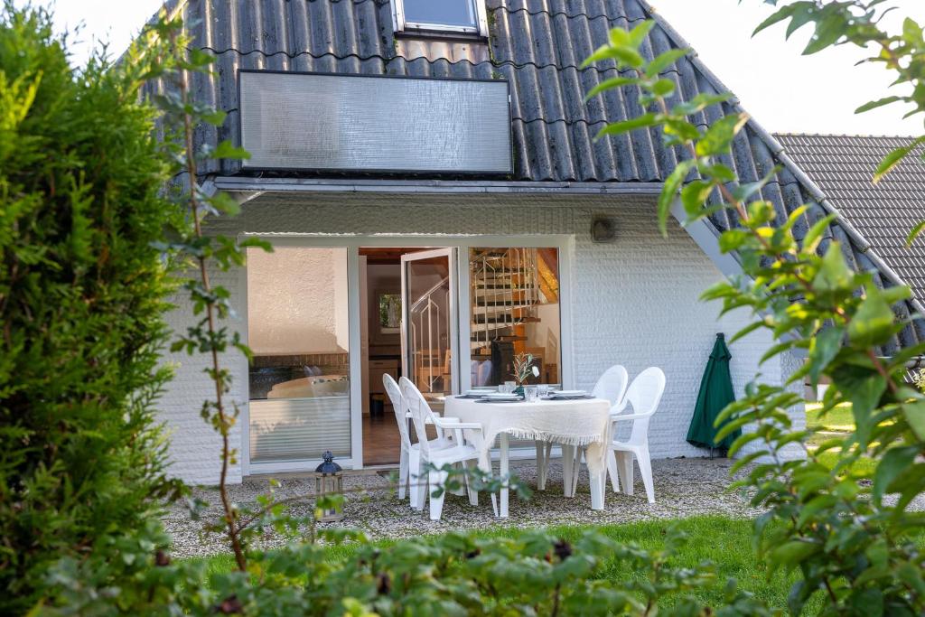 a white table and chairs in front of a house at OH1 - Strandvogt Komfort in Dorum-Neufeld