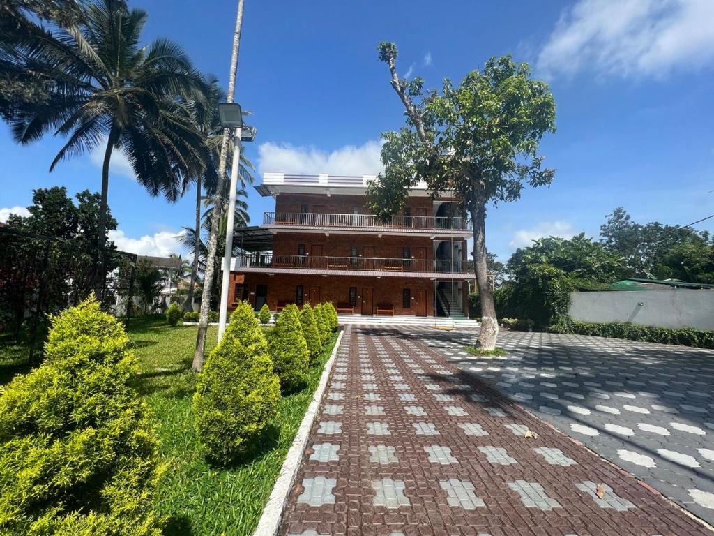 un bâtiment avec un palmier et une passerelle en briques dans l'établissement DOLPHIN ENCLAVE SERVICE STUDIO APARTMENTS, à Kalpatta
