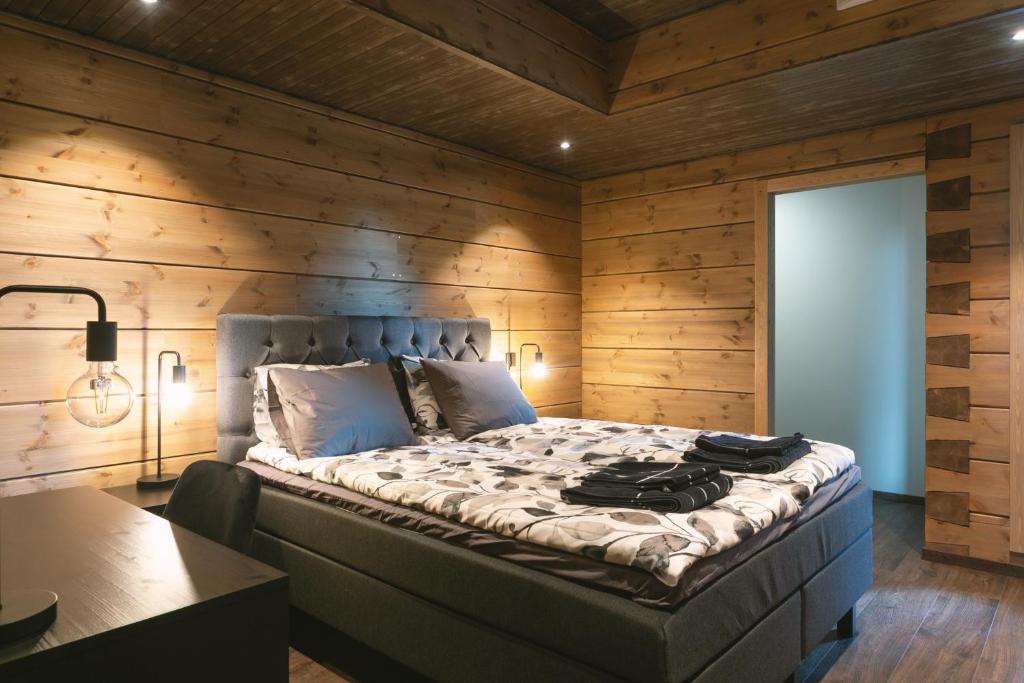 a bedroom with a large bed with wooden walls at Luxury Villa Lapland in Rovaniemi