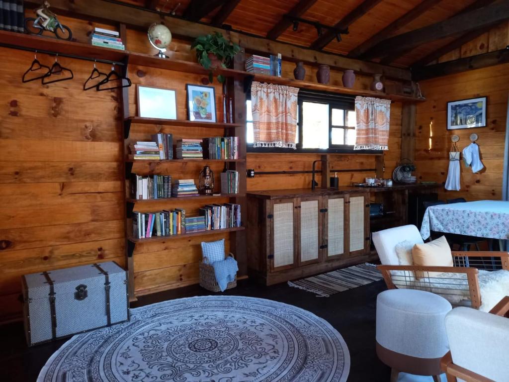 a living room with wooden walls and a room with bookshelves at Cabana Van Gogh in Campo Alegre