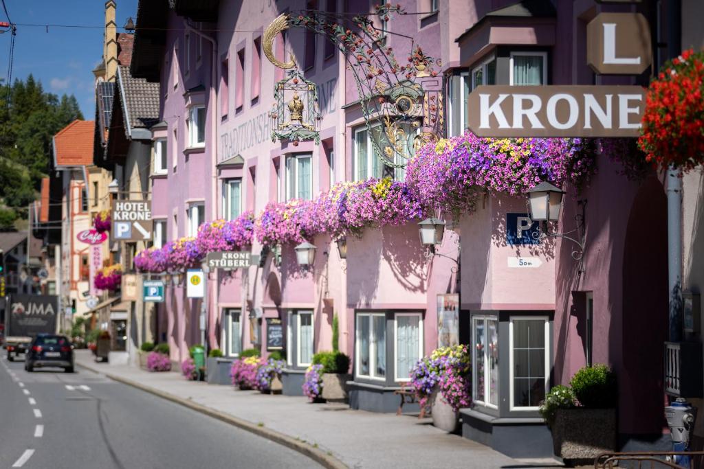 uma rua repleta de edifícios cor-de-rosa com flores roxas em Hotel Krone em Matrei am Brenner