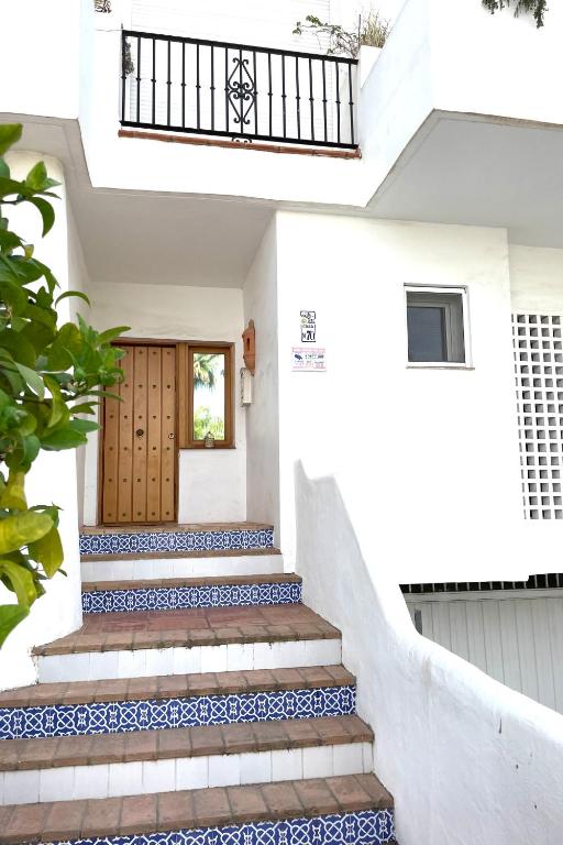 dom z niebiesko-białymi schodami i drewnianymi drzwiami w obiekcie FANTASTIQUE MAISON DE VILLE A COSTALITA w mieście Estepona