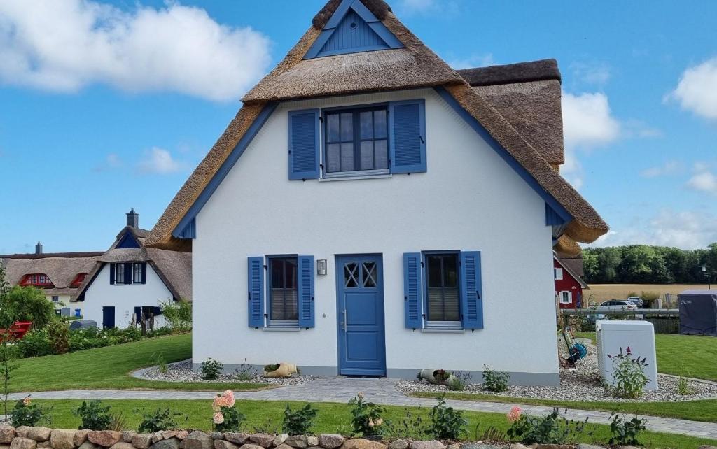 a cottage with a thatched roof and blue shutters at Reethaus "Dat Lavendelhus" in Zierow