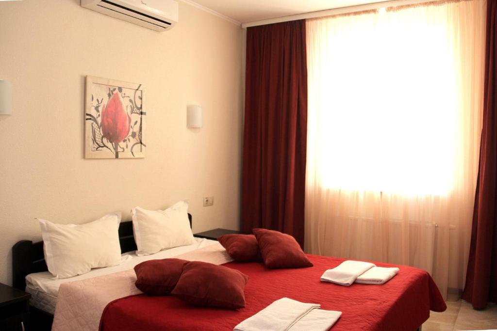 a bedroom with two beds with red sheets and a window at Breeze Hotel in Odesa