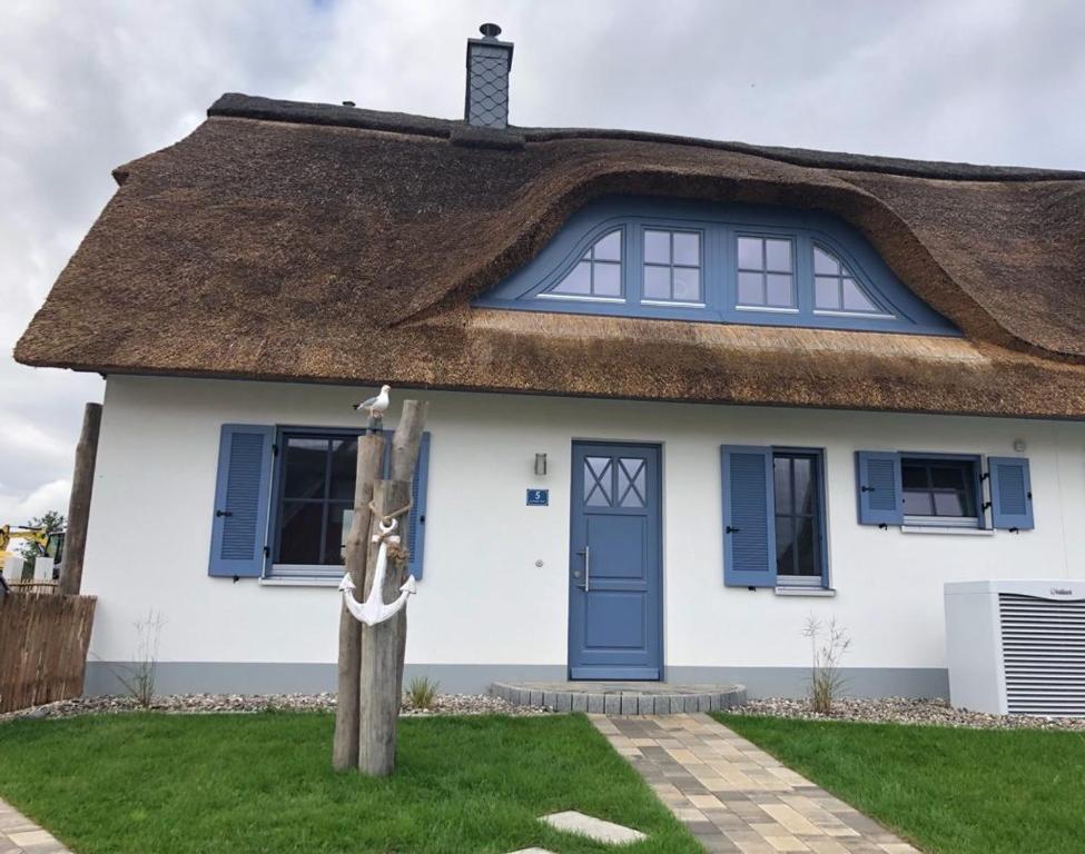 a thatch roof house with a blue door at Reethaus "dat huus" in Zierow