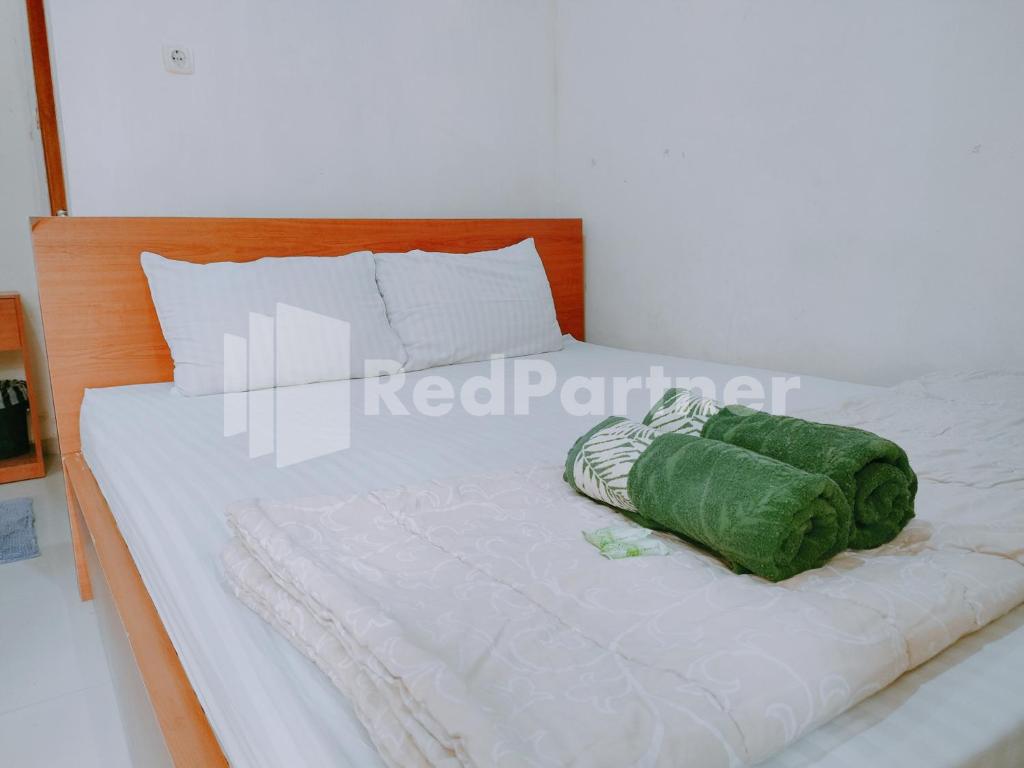 een wit bed met een groen kussen erop bij Calida Hotel Mitra RedDoorz near Alun Alun Wonosari in Wonosari