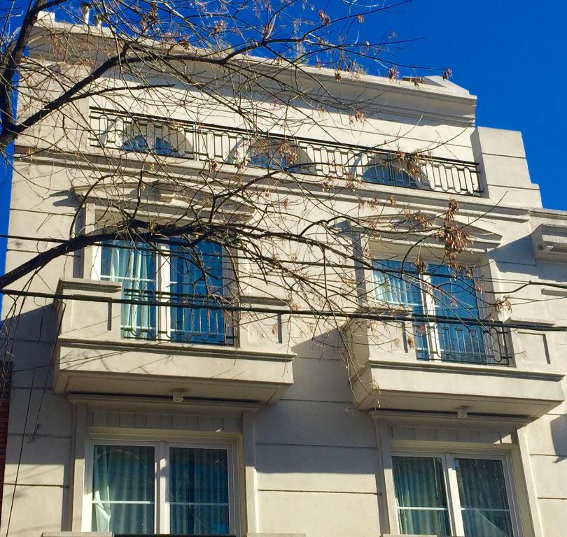 a white building with blue windows and a tree at Purobaires Hotel Boutique in Buenos Aires