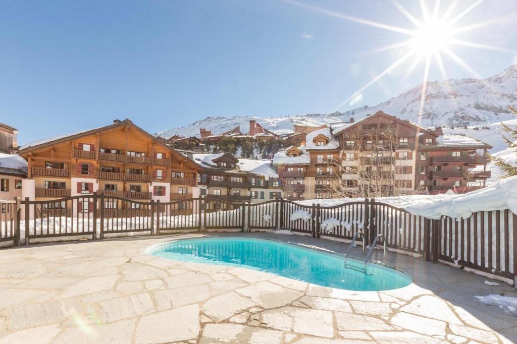 uma piscina com montanhas cobertas de neve ao fundo em Résidence & Spa Les Sources de Marie - Arc 1950 Le Village em Arc 1950