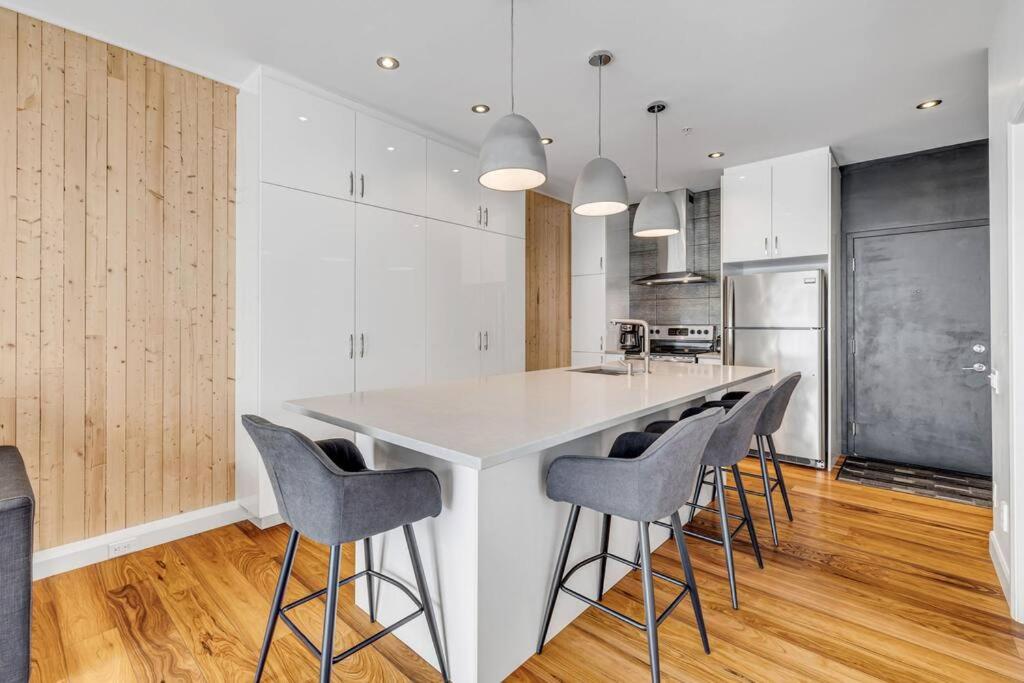 a kitchen with a white island with bar stools at Initial / Ilot / Downtown Québec in Quebec City