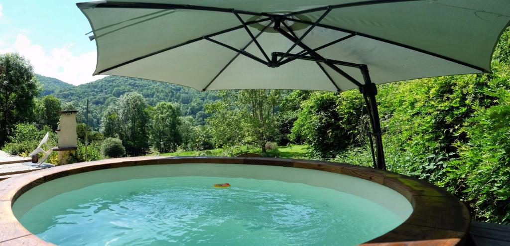 a hot tub with an umbrella in the middle of a field at Sport et réconfort en Couserans in Soulan