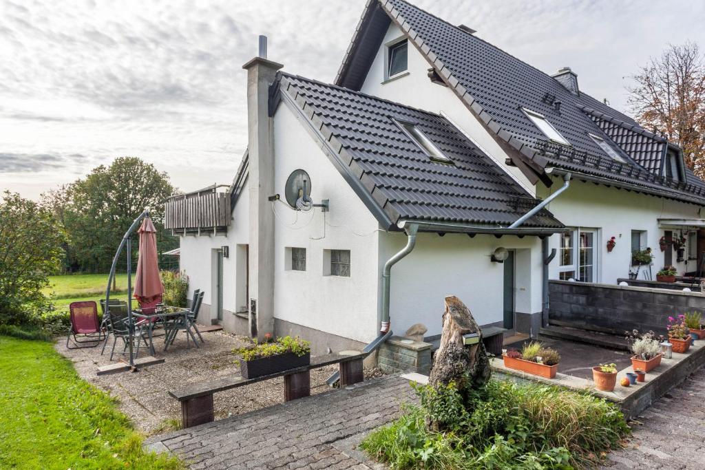 ein weißes Haus mit einer Terrasse davor in der Unterkunft Ferienwohnungen Zum Hasenbahnhof in Kirchhundem