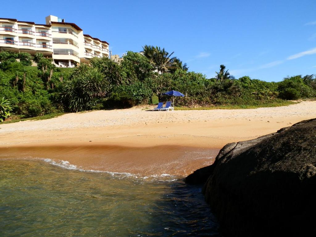 a beach with a chair and an umbrella on the sand at Setiba Pousada Park in Guarapari