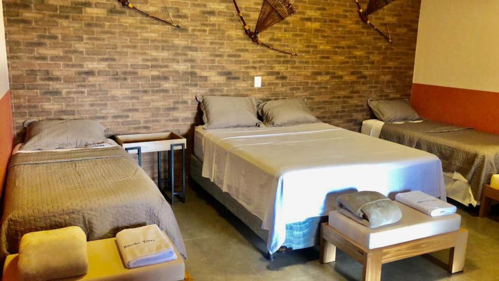 a room with two beds and a brick wall at Rancho Terra in Dourados
