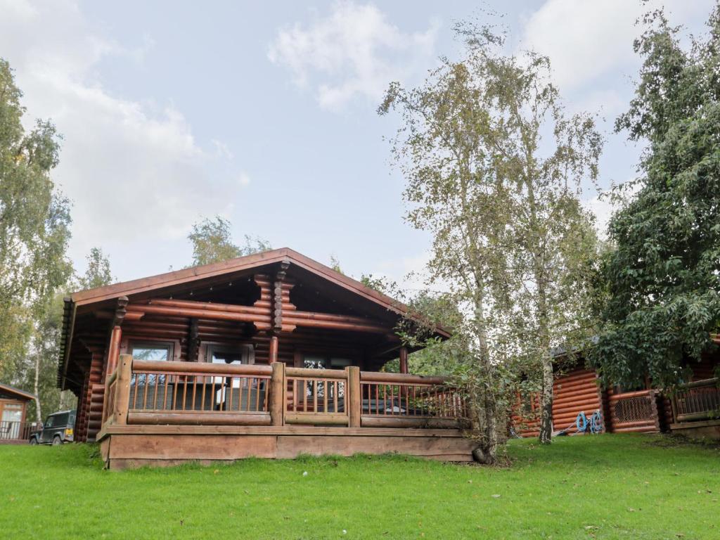 a log cabin with a deck in the grass at 10 Water's Edge in Morpeth