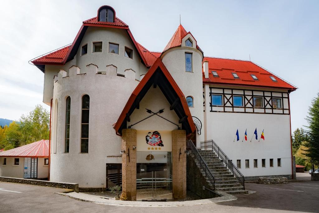 ein großes weißes Gebäude mit rotem Dach in der Unterkunft House of Dracula Hotel in Poiana Brașov