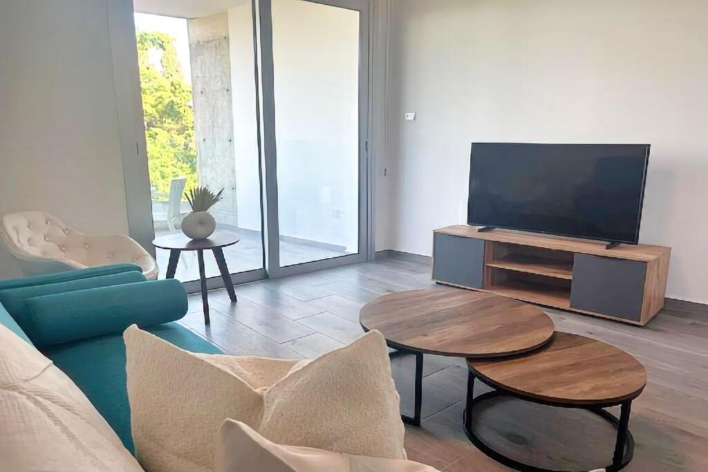 uma sala de estar com um sofá azul e uma televisão em Phaedrus Living Coral Suites Harmony em Lárnaca