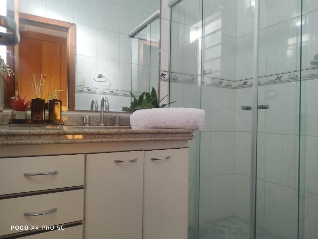 y baño con ducha acristalada y lavamanos. en Quarto Suite - SAVASSI BH, en Belo Horizonte