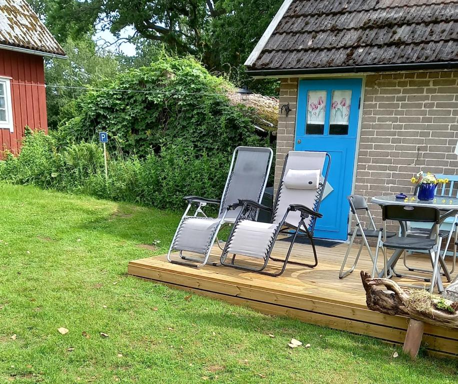 a deck with chairs and a table in a yard at Lunden in Vittaryd