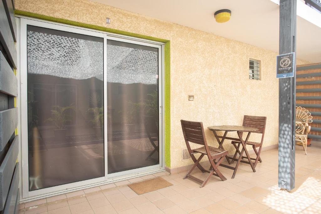 a patio with a sliding glass door with a table and chairs at 1- VACOA - CHAMBRE 1 - Rdc G in La Saline les Bains