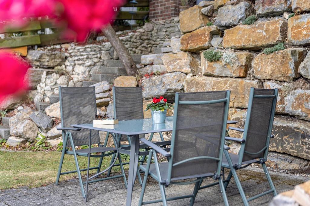 a table with three chairs and a table with flowers at Südalb in Albstadt