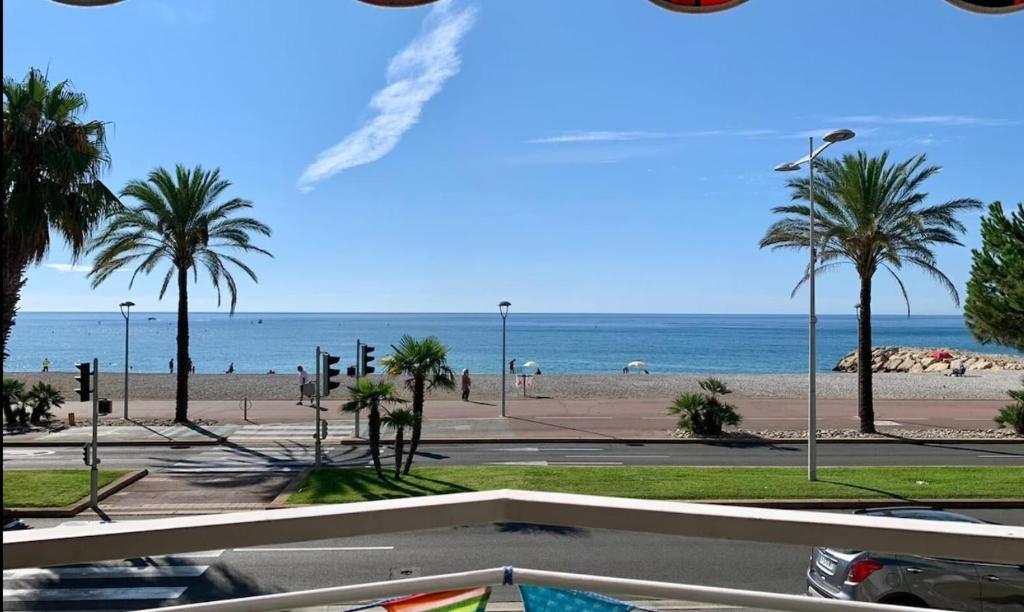 une vue sur une plage avec des palmiers et l'océan dans l'établissement Le Chantilly, à Cagnes-sur-Mer